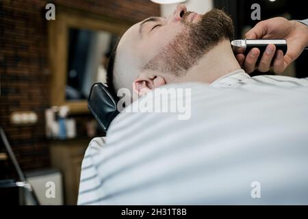 Professionelle Bartrasur in einem Friseurladen. Ein Mann bekommt einen Haarschnitt Stockfoto