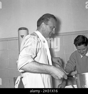 Der Schracken der Hausfrau: Vater und Sohn bei der Aufbereitung eines Nudelsalats, Deutschland 1958. Hausfrauen in Panik: Vater und Sohn bereiten einen Nudelsalat zu, Deutschland 1958. Stockfoto