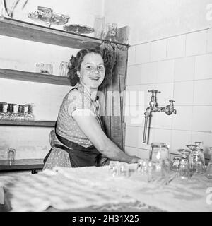 Junge Frau spült in der Küche im Gasthaus, Deutschland 1955. Eine junge Frau, die in einer Kneipe die Gläser putzt, Deutschland 1955- Stockfoto