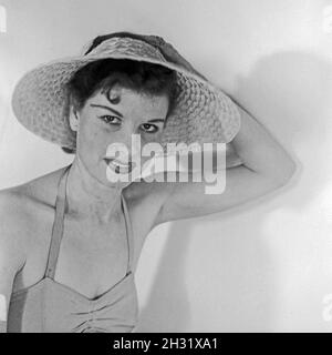 Eine junge Frau mit Sonnenhut positioniert für den Fotografen, Deutschland 1958. Eine junge Frau mit einem Hut, der für den Fotografen posiert, Deutschland 1958. Stockfoto