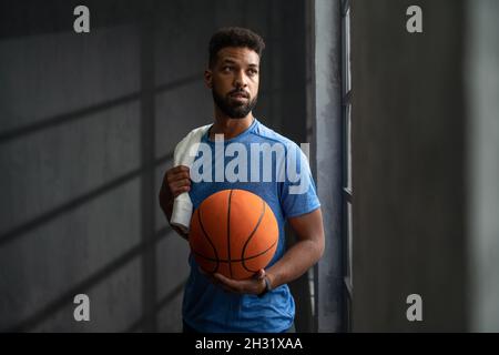 Junger afroamerikanischer Basketballspieler, der im Fitnessstudio steht. Stockfoto