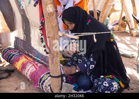 Eine Frau webt auf einem traditionellen Webstuhl in der Wüste der Sahara. Stockfoto