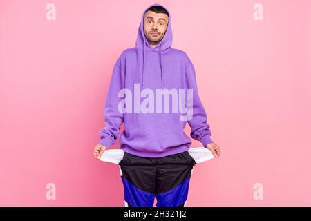 Foto von beeindruckt Millennial Brunet Kerl tragen violette Hoodie isoliert auf rosa Hintergrund Stockfoto