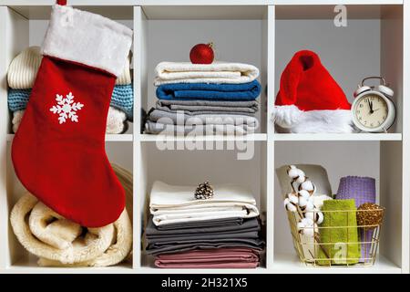 Organisation der Lagerung. Bettwäsche, Handtücher, Bettwäsche, Decken auf den Regalen sind zur Feier von Weihnachten und Neujahr dekoriert. Stockfoto