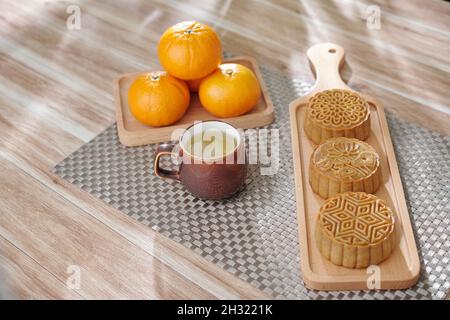 Tasse Kräutertee, Mondkuchen und Mandarinen werden zum traditionellen Fest serviert Stockfoto