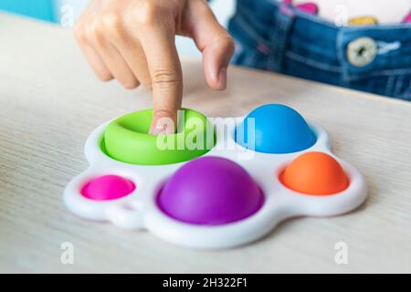 Portrait Mädchen mit modernen einfachen Grübchen Spielzeug. Bunt und hell Pop es Spielzeug einfache Grübchen. Trendy Antistress Sinnesspielzeug Fidget Push Pop it. Lustig gir Stockfoto