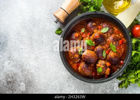 Frikadellen in Tomatensoße in einer Pfanne auf dunklen Tisch aus Stein. Stockfoto