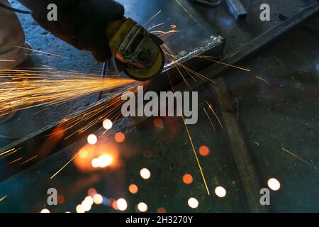 Industriearbeiter mit Winkelschleifer Schleifen Metall auf Schweißnähten. Arbeiter, die mit Winkelschleifer arbeiten und Funken haben. Werkzeug für geschnittenen Stahl. Sicherheit Stockfoto