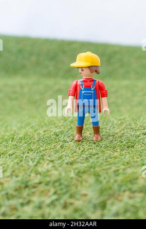 Kleines Spielzeug Playmobil Landwirt Figur steht in "Feld" aus faux / gefälschte Gras. Für die britische Lebensmittelproduktion: Farm to Fork, Field to Fork / Field to Plate. Stockfoto