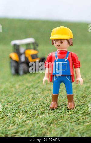 Kleiner Spielzeugtraktor auf faux / gefälschtem Gras mit Spielzeug Playmobil Landwirt Figur. Für die britische Lebensmittelproduktion: Farm to Fork, Field to Fork / Field to Plate Stockfoto