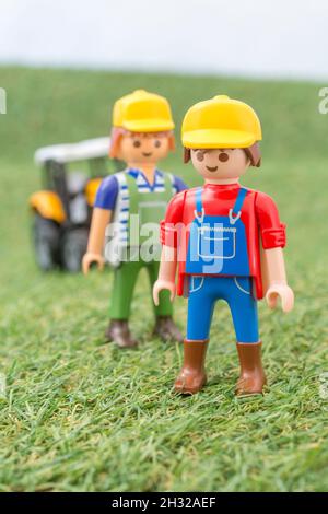 Kleiner Spielzeugtraktor auf faux / gefälschtem Gras mit Spielzeug Playmobil Landwirt Figur. Für die britische Lebensmittelproduktion: Farm to Fork, Field to Fork / Field to Plate Stockfoto