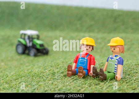 Kleiner Spielzeugtraktor auf faux / gefälschtem Gras mit Spielzeug Playmobil Landwirt Figur. Für die britische Lebensmittelproduktion: Farm to Fork, Field to Fork / Field to Plate Stockfoto
