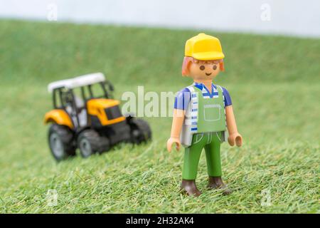 Kleiner Spielzeugtraktor auf faux / gefälschtem Gras mit Spielzeug Playmobil Landwirt Figur. Für die britische Lebensmittelproduktion: Farm to Fork, Field to Fork / Field to Plate Stockfoto