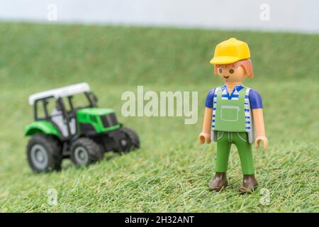 Kleiner Spielzeugtraktor auf faux / gefälschtem Gras mit Spielzeug Playmobil Landwirt Figur. Für die britische Lebensmittelproduktion: Farm to Fork, Field to Fork / Field to Plate Stockfoto