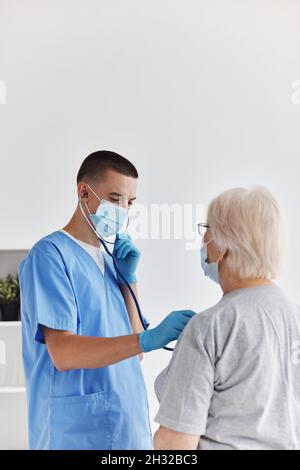 Arzt in medizinischer Maske hört der Patientenuntersuchung zu Stockfoto