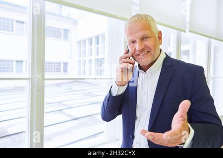 Älterer Mann als Unternehmer oder Unternehmensberater nutzt sein Smartphone, um zu telefonieren Stockfoto