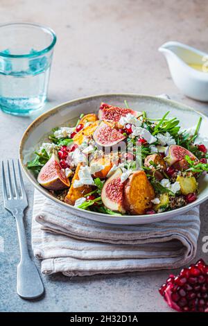 Warmer herbstlicher Quinoa-Salat mit gebackenem Gemüse (Süßkartoffeln, Rosenkohl), Feigen, Feta-Käse und Granatapfel. Stockfoto