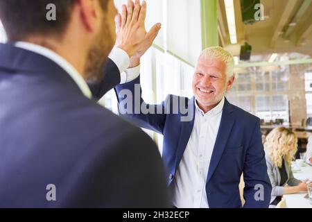 Leitender Geschäftsmann als Manager, der einem Geschäftspartner ein hohes Fünftel gibt Stockfoto