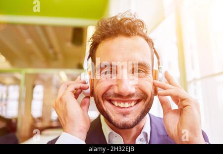 Ein junger lächelnder Geschäftsmann mit Kopfhörern, der im Büro eine Videokonferenz abhalten kann Stockfoto