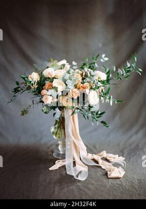 Vintage Hochzeitsstrauß. Schönes Brautstrauß in Pfirsich- und Beigetönen auf dunkelgrauem Hintergrund. Blumen-Einladungskarte. Elegante Hochzeitsinspiration Stockfoto