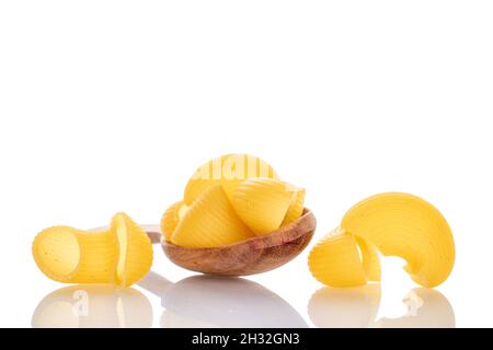 Hellgelbe, ungekochte Pasta mit einem Holzlöffel, Nahaufnahme, isoliert auf Weiß. Stockfoto
