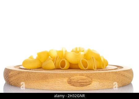 Hellgelbe, ungekochte Pasta auf einem Holztablett, Nahaufnahme, isoliert auf Weiß. Stockfoto
