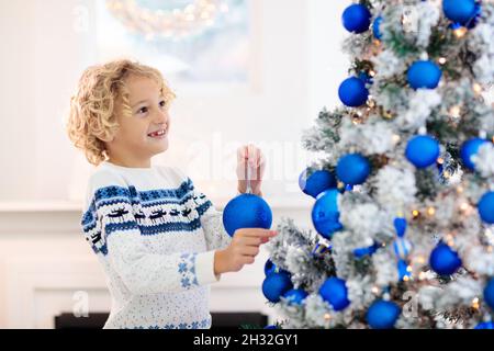 Kinder dekorieren Weihnachten zu Hause. Eröffnungsgeschenke und Geschenke am Weihnachtsmorgen. Blau und weiß Weihnachten Dekoration Thema. Stockfoto