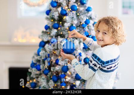 Kinder dekorieren Weihnachten zu Hause. Eröffnungsgeschenke und Geschenke am Weihnachtsmorgen. Blau und weiß Weihnachten Dekoration Thema. Stockfoto