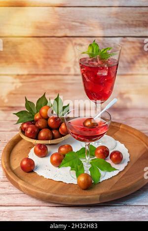 Hausgemachte rote Kirschpflaume in einem Weinglas auf Holzhintergrund Stockfoto