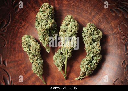 Cannabisknospen in brauner Tonschale, flacher Lat, Draufsicht. Marihuana-Blüten aus nächster Nähe. Hanf Erholung, Canna Küche, Legalisierungskonzept. Stockfoto