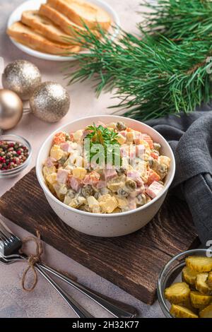 Olivier-Salat aus fein gehacktem Gemüse und Wurst auf hellem Hintergrund. Stockfoto