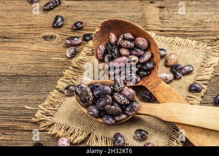 Verschiedene bunte Bohnen in großen Holzlöffeln. Rohe gesunde Zutat für das Kochen von nützlichen Lebensmitteln. Alter Holztisch, Platz zum Kopieren Stockfoto