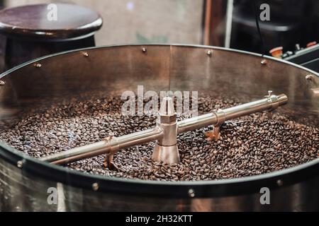 Röstung von frischen Kaffeebohnen in der Fabrik. Metalltrommel voller Kaffeebohnen Stockfoto