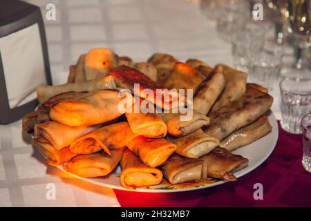 Russisches Fest. Ein Tischset mit russischen Snacks: Pancakes Bliny mit Füllung. Stockfoto