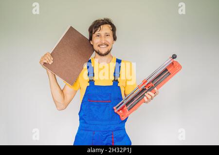 Ein Fliesenleger, ein Fliesenspezialist, hält einen Fliesenschneider in den Händen Stockfoto