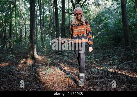 Frau, die in einem Wald mit Stöcken Feuer sammeln Stockfoto