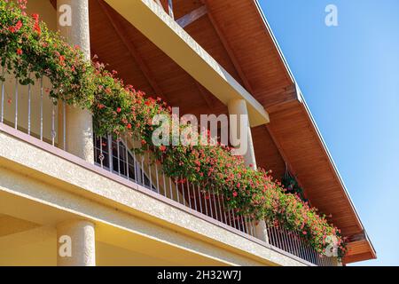 Teil des Hauses mit einer schönen Terrasse und einem Balkon mit Blumen. Stockfoto