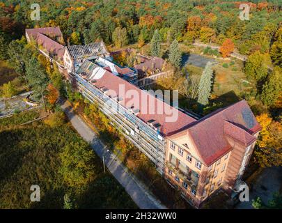 Beelitz, Deutschland. Oktober 2021. Das Operationsgebäude auf dem Gelände der ehemaligen Lungenheilanstalten in Beelitz-Heilstätten. Der 320 Meter lange Baumwipfel-Spaziergang befindet sich auf dem Gelände. Von der Stahl- und Holzkonstruktion über den Baumkronen aus können Besucher die denkmalgeschützten Gebäude und den Park besichtigen. (Luftaufnahme mit einer Drohne) Quelle: Monika Skolimowska/dpa-Zentralbild/dpa/Alamy Live News Stockfoto