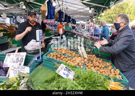 Gemüsehändler in Großbritannien, der während der COVID 19-Pandemie Gemüse in einer Maske an einen Kunden verkauft, Salisbury Market, Salisbury Wiltshire UK Stockfoto