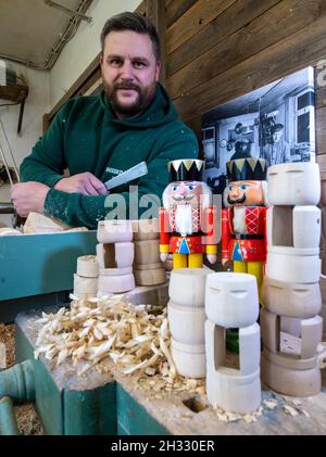 25. Oktober 2021, Sachsen, Seiffen: Der Holzspielzeughersteller Markus Füchtner steht an der Drehbank in seiner Werkstatt in Seiffen. 1870 soll Füchtners Ur-Ur-Urgroßvater den ersten Erzgebirge-Nussknacker gemacht haben, denn er steht heute weltweit neben Rauchern und Pyramiden für das Erzgebirge. Das Handwerk setzt die alte Tradition fort und hat nun erstmals einen Mini-Nussknacker in den Weltraum geflogen. Der Nussknacker, benannt nach dem Gründer Wilhelm Füchtner, hat seine Heimat im Erzgebirge gegen den Weltraum gehandelt. Bald wird er seinen großen Auftritt auf den ISS-Raumauftritten haben Stockfoto