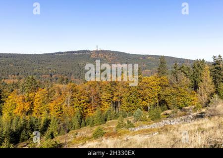 Die Sonne scheint bei blauem Himmel im Taunus mit dem herbstlich verfärbten Wald - Blick auf den Großen Feldberg. Stockfoto