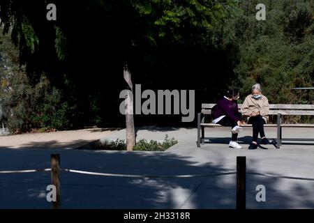 Alte Frau und Pflegen saßen auf der Bank, Barcelona, Spanien. Stockfoto