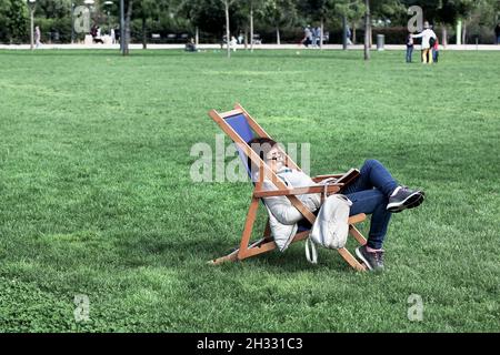 Frau sackte im Liegestuhl und las. Stockfoto