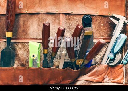 Meißel und andere Arbeitswerkzeuge für die Holzbearbeitung und Zimmerei in Leder-Werkzeuggürtel Stockfoto