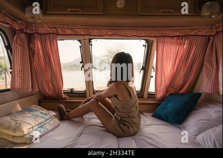 Schöne junge asiatische Frau, die sich abends entspannt und die Aussicht im Wohnheim auf dem Campingplatz ausschaut Stockfoto