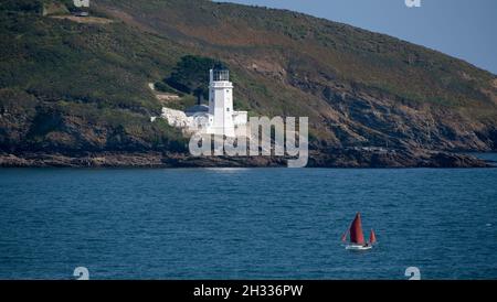 Falmouth, Cornwall, England, Großbritannien. 2021. St Anthony's Lighthouse mit einem Segelboot unter Wasser über die Carrock Roads, in der Nähe von Falmouth, Cornwall Stockfoto