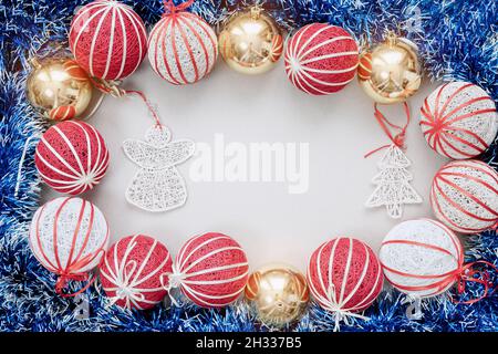 Handgefertigte Weihnachtsbaumdekorationen und blauer Lametta sind auf weißem Hintergrund angeordnet. Draufsicht Stockfoto