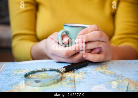 Junge Frau trinkt Kaffee und plant Welttournee mit Vintage Travel Map - Backpacker Mädchen auf der Suche nach einem neuen Land zu erkunden - Reisetrends, Stockfoto