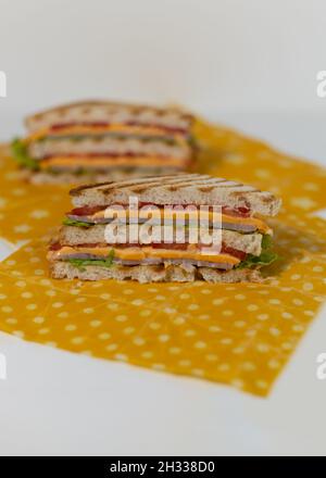 Ein traditionelles Sandwich aus getoasteten Brotscheiben, Käse, Schinken und frischem Salat, eingewickelt in wiederverwendbares Bienenwachspapier aus biologischem Anbau. Wir Feiern National Sandwi Stockfoto