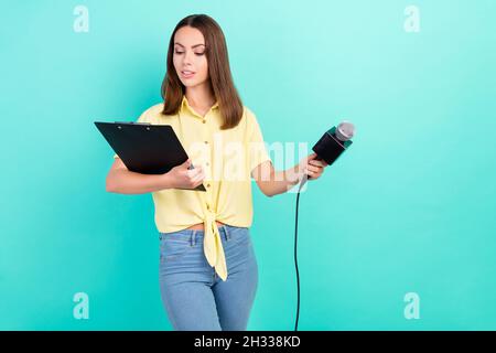 Foto von denken junge Brünette Dame nehmen Interview lesen Papier tragen gelbe Top Jeans isoliert auf blauem Hintergrund Stockfoto